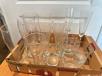 Front view of all clear glass drinkware in cardboard tray