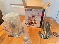 Open box showing branded packaging, bubble-wrapped components and one mug part