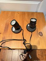 Two black plug-in spotlights on wooden surface