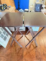 Pair of dark brown folding tray tables standing side by side