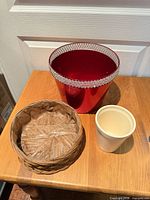 All three containers on table: red metal planter, wicker basket, white pot