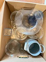 Top view of cardboard box containing assorted clear glass vases and galvanized metal bucket