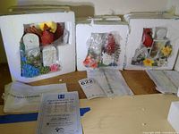 Three styrofoam packages each holding a porcelain cardinal figurine with accessories