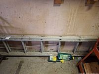 Full view of ladder lying on floor against wall