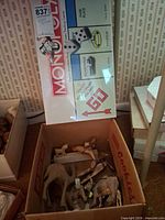 Monopoly game box leaning against wall with box of wooden animals below
