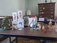 Table overview showing boxed Hallmark ornaments, wooden tree, tin, figurines