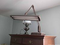 Brown adjustable-arm fluorescent desk lamp on dresser