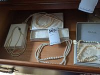Overview of four simulated pearl necklaces in drawer with boxes
