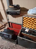 Three Kodak slide projectors with two open carrying cases