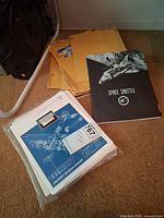 Overall lot showing technical drawing portfolio, Space Shuttle booklet, and manila envelopes