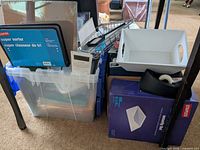 Overview of plastic bin with Staples Super Sorter, white tray, binders, purple box, tape dispenser