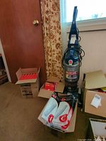 Vacuum cleaner with surrounding boxes of vacuum bags