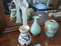 Group of four vases on dresser in front of mirror