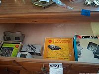Drawer showing View-Master viewer, Kodak Carousel Stack Loader box, GAF Pana-Vue viewer box, GE lamp box, reel packet