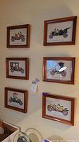 All six framed embroidered automobile pictures on wall