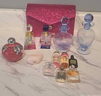 Group shot showing makeup bag, crystal bottles, blue decanter bottles, Nina Ricci apple bottle and sample perfumes