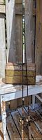 Two spinning rods leaned against closed vintage tackle box