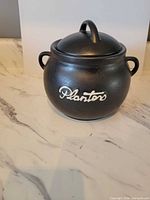 Front view of black ceramic Planters jar with lid and handles