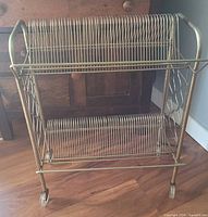 Front view showing two wire shelves, gold-tone finish, front casters, overall structure