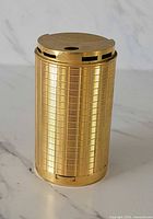 Full view of cylindrical gold-plated Vinci table lighter showing grid pattern