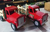 Front view of both wooden trucks showing cab color, decals, grille, wheels