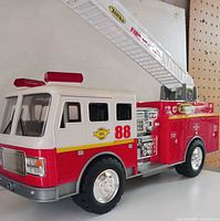 Left front view of Tonka fire rescue ladder truck showing cab, wheels, ladder base and decals