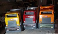 Front view of three Little Tikes dump trucks showing cab colors and grills