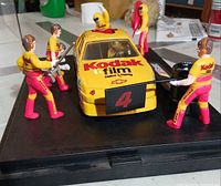 Front angled view of model car with pit crew on base