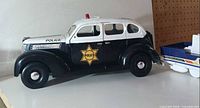 side view of black and white police sedan toy