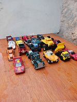 20 assorted toy vehicles lined up on wooden surface