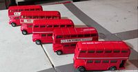 Front angled view of all six red double-decker model buses lined up