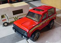 Red Ford Bronco toy and white Winnebago camper side view