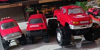 Front view of the three red pickup toy trucks