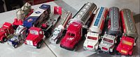 Eight diecast trucks lined up showing variety of trailers