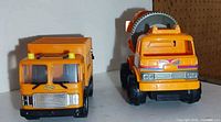 Front view of both orange toy trucks side by side