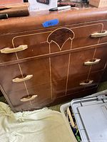 Front view of Art Deco dresser showing three drawers, veneer pattern, handles, and surface wear