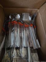 bundled stainless forks, spoons, serving fork inside box