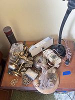 Overview of entire lot on tabletop showing lamp, candlesticks, hardware, trinket box