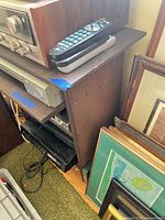 Angled view of rack with cassette deck, receiver, VCR, black component, remote; shows veneer finish and wear