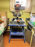 Full view of Craftsman radial arm saw on stand with accessories on table