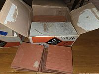 Open Domco boxes with stacks of 6 in red terracotta vinyl tiles
