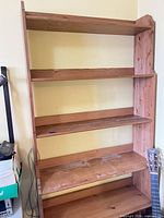 Full front view of tall five-shelf solid wood bookcase showing color, shelves and wear