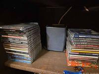Two stacks of jewel-case audio CDs on shelf
