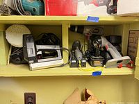 Shelf view showing both sanders, chargers, drill, work light, battery and buffing pad