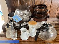 Overall view showing amber glass casseroles, coffee carafe, stainless bowl set, small glass and ceramic pieces