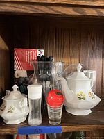 Front view of ceramic teapot set, spice shakers, utensil-filled vase, boxed items visible