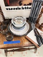 All items displayed on chair: tumblers, pie dish, bowls, plates, apple slicer, knives, skewers pack, cutting board, Guzzini tray box