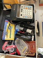 Overall view inside case showing calculator, stapler, tapes, compass, flashlight