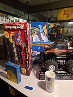 Group shot showing boxed Micro Machines, Hot Wheels, Learning Resources clock, RC monster truck and partial K’NEX box
