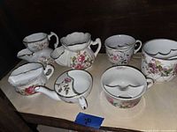 Group shot of creamer, five moustache cups and shaving scuttle